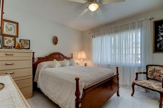 bedroom with light hardwood / wood-style flooring, a textured ceiling, and ceiling fan