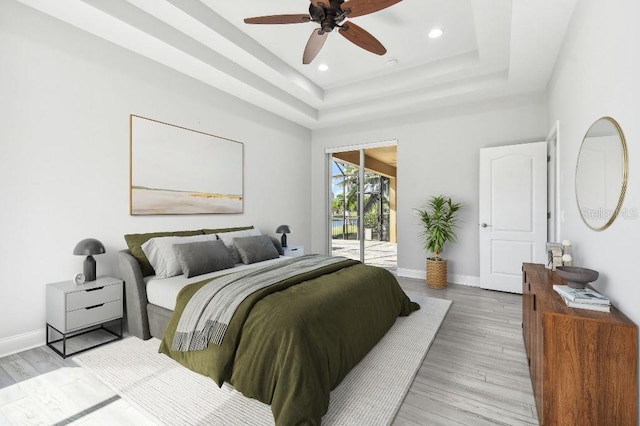 bedroom featuring access to outside, wood-type flooring, ceiling fan, and a raised ceiling