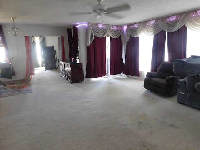 unfurnished living room with plenty of natural light, ceiling fan, a textured ceiling, and light carpet