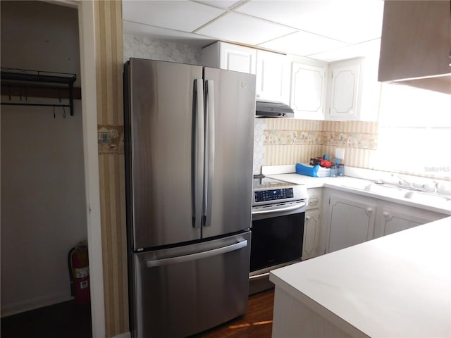 kitchen with decorative backsplash, stainless steel appliances, sink, white cabinetry, and range hood