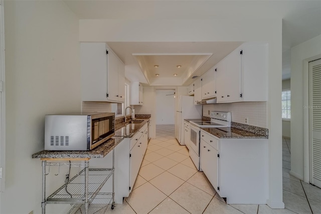 kitchen featuring white cabinetry, sink, white appliances, and dark stone countertops