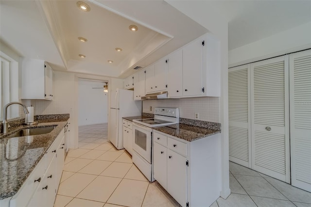 kitchen featuring tasteful backsplash, sink, white cabinets, dark stone countertops, and white appliances