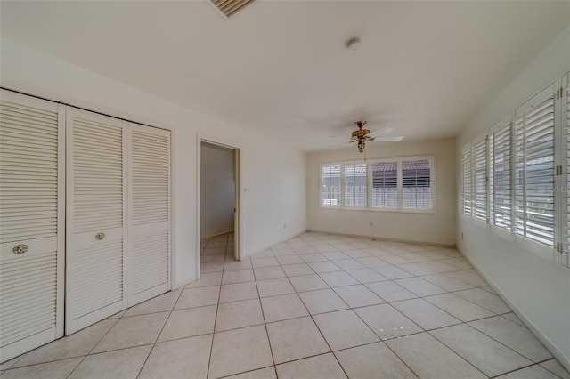 unfurnished bedroom featuring ceiling fan, light tile patterned floors, and a closet