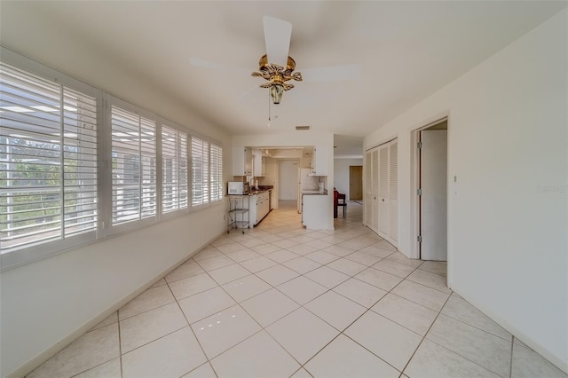 empty room with ceiling fan and light tile patterned floors