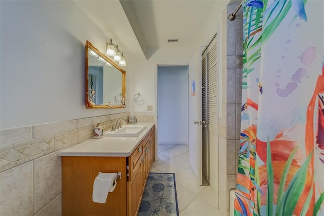 bathroom featuring vanity, walk in shower, tile patterned flooring, and tile walls