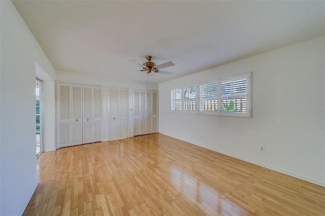 unfurnished bedroom with multiple closets, light hardwood / wood-style flooring, and ceiling fan