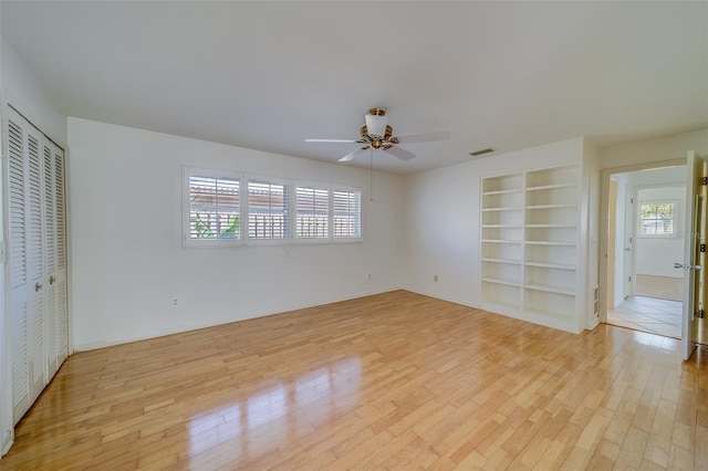 unfurnished bedroom with ceiling fan, multiple windows, and light wood-type flooring