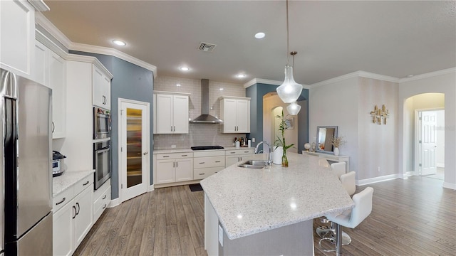 kitchen featuring wall chimney range hood, stainless steel refrigerator, sink, an island with sink, and hardwood / wood-style flooring