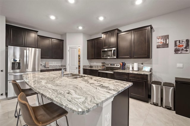 kitchen featuring a kitchen bar, appliances with stainless steel finishes, and a kitchen island with sink