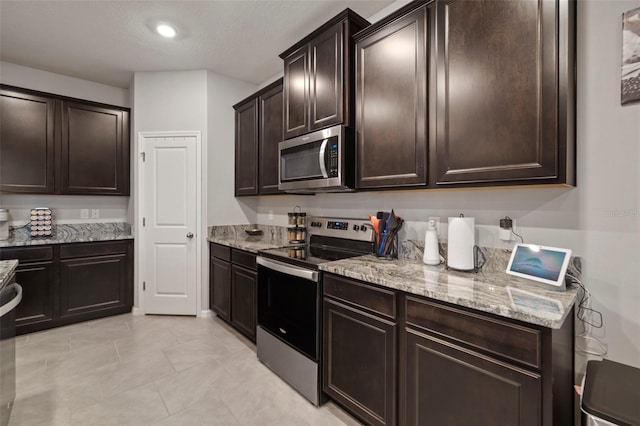 kitchen featuring light tile patterned flooring, stainless steel appliances, dark brown cabinetry, and light stone countertops