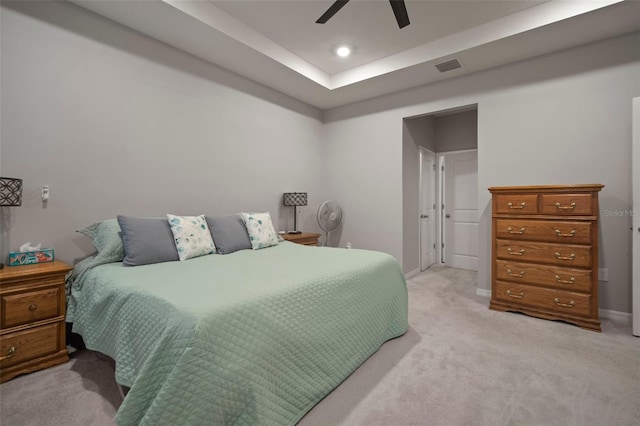 carpeted bedroom with ceiling fan and a tray ceiling