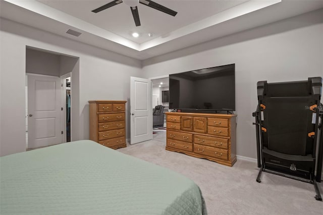 bedroom featuring light carpet, ceiling fan, and a raised ceiling