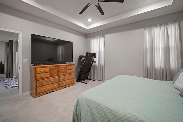 bedroom featuring ceiling fan, light carpet, and a raised ceiling