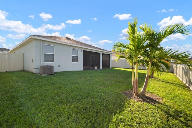 rear view of property featuring a sunroom, cooling unit, and a lawn