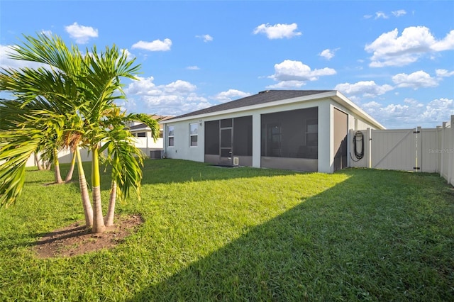 rear view of property with central air condition unit, a yard, and a sunroom