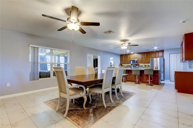 dining space featuring ceiling fan, sink, and a textured ceiling