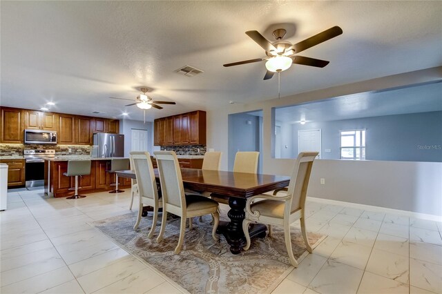 dining area with ceiling fan and a textured ceiling