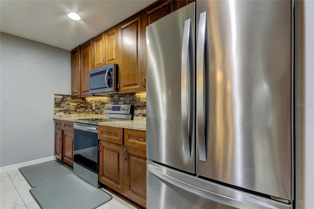 kitchen with light stone countertops, stainless steel appliances, and tasteful backsplash