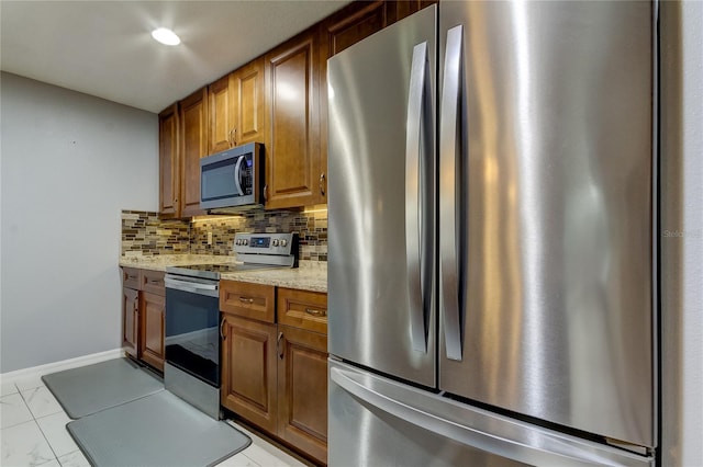 5220 Butterfly Shell Dr, Apollo Beach, FL 33572 - kitchen with stainless steel appliances, backsplash, brown cabinets, light stone countertops, and baseboards