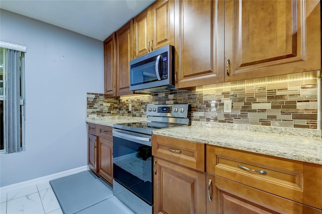 5220 Butterfly Shell Dr, Apollo Beach, FL 33572 - kitchen featuring appliances with stainless steel finishes, light stone counters, tasteful backsplash, and brown cabinetry