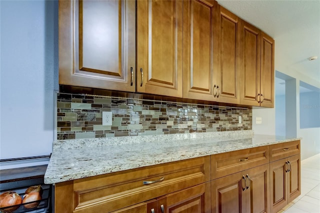 kitchen with light tile patterned flooring, light stone countertops, and backsplash