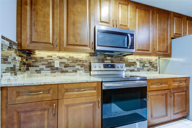 5220 Butterfly Shell Dr, Apollo Beach, FL 33572 - kitchen with appliances with stainless steel finishes, light stone counters, tasteful backsplash, and brown cabinets