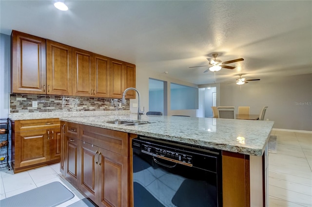 kitchen with dishwasher, sink, light stone counters, an island with sink, and decorative backsplash