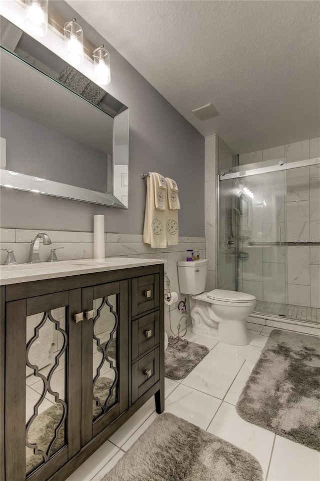 bathroom featuring vanity, tile patterned floors, toilet, a textured ceiling, and walk in shower