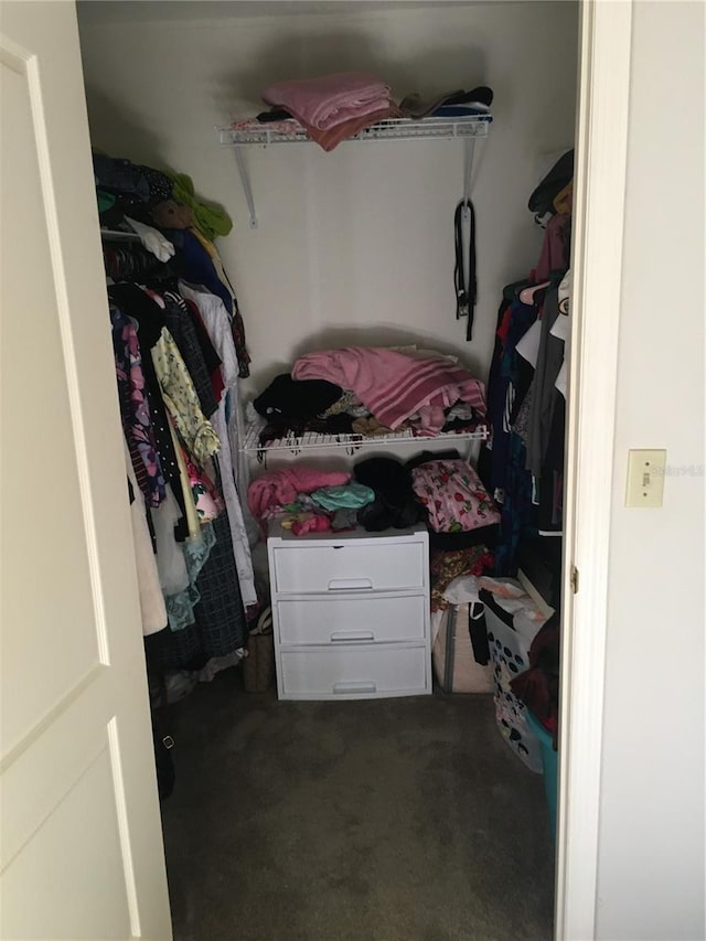 walk in closet with dark carpet