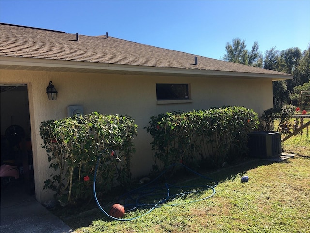 view of side of property featuring a yard and central AC