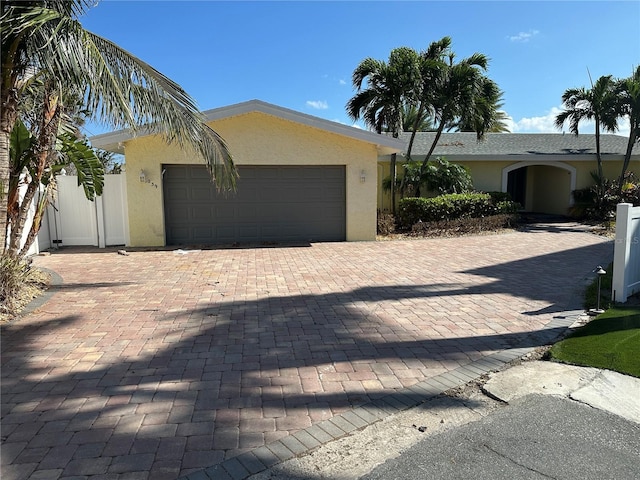 ranch-style home with stucco siding, a garage, and driveway