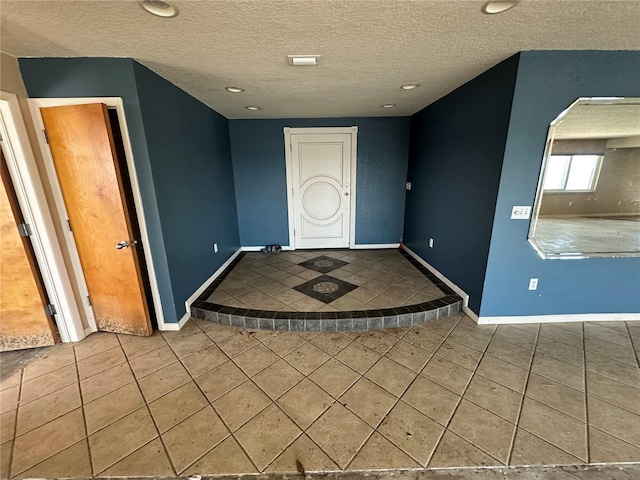 entrance foyer with baseboards, a textured ceiling, and tile patterned flooring