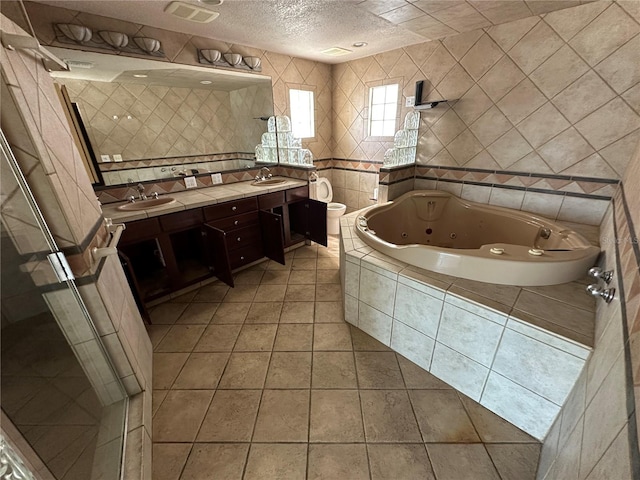 full bath featuring visible vents, a sink, tile patterned flooring, a shower stall, and a textured ceiling