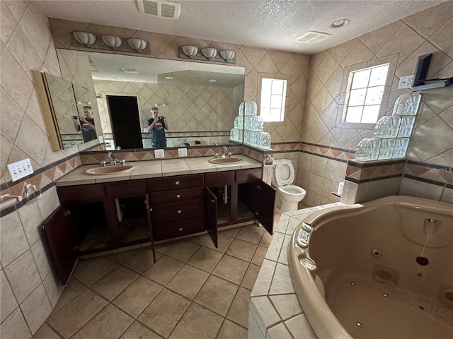 bathroom with toilet, tile walls, a textured ceiling, vanity, and a bath