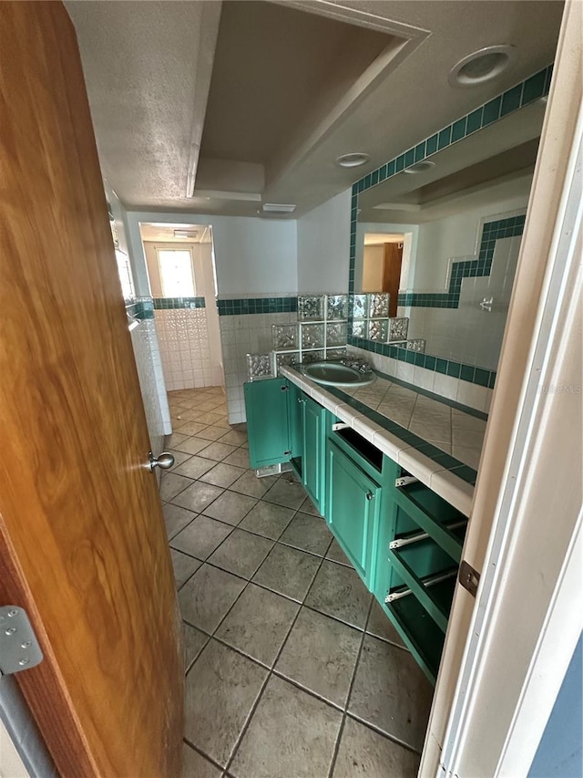 bathroom with vanity, tile patterned floors, tile walls, and a tray ceiling