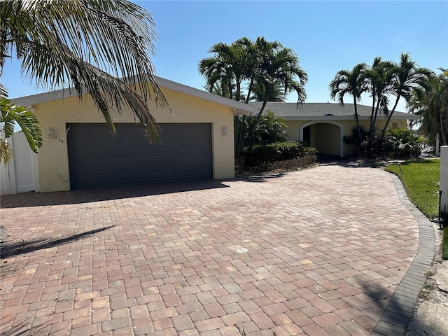 ranch-style home with decorative driveway, an attached garage, and stucco siding