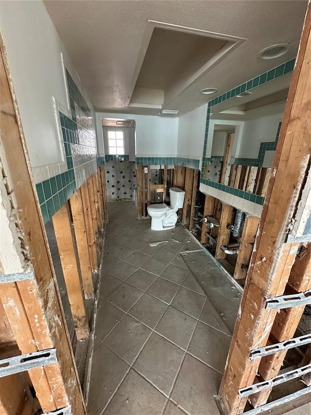 bathroom featuring toilet, wainscoting, and tile patterned flooring