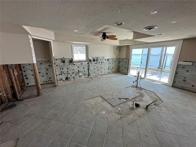 spare room with tile patterned floors, a ceiling fan, visible vents, and a textured ceiling