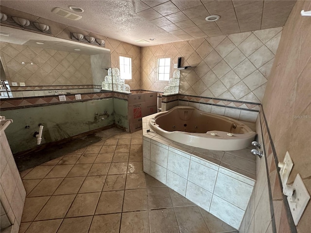 full bathroom with a tub with jets, a textured ceiling, tile walls, and tile patterned flooring