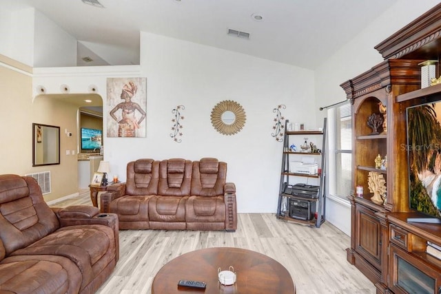 living room featuring high vaulted ceiling and light hardwood / wood-style flooring