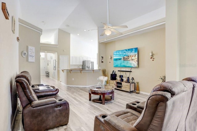 living room featuring high vaulted ceiling, sink, light wood-type flooring, and ceiling fan