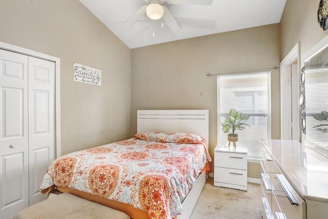 bedroom featuring a closet, light colored carpet, vaulted ceiling, and ceiling fan