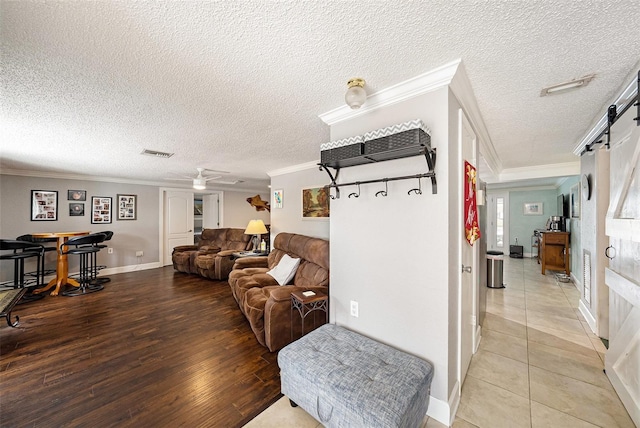 interior space featuring hardwood / wood-style floors, a barn door, crown molding, and a textured ceiling