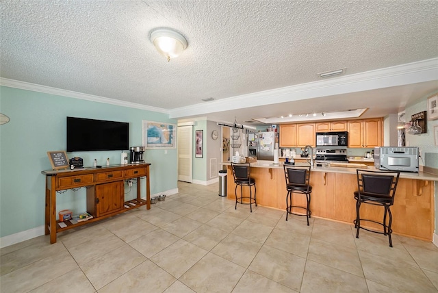 kitchen with a kitchen breakfast bar, kitchen peninsula, crown molding, and appliances with stainless steel finishes