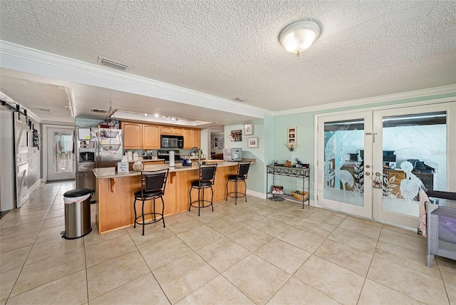 kitchen featuring a breakfast bar, crown molding, a barn door, a textured ceiling, and kitchen peninsula