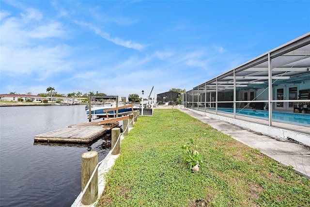 dock area with a lanai, a yard, and a water view