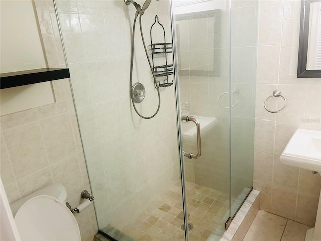 bathroom featuring toilet, sink, and a shower with shower door