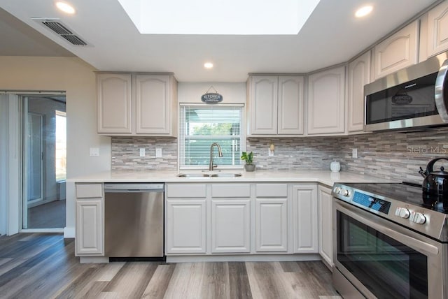 kitchen with light hardwood / wood-style floors, sink, appliances with stainless steel finishes, and tasteful backsplash