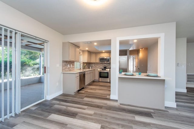 kitchen with light hardwood / wood-style floors, sink, appliances with stainless steel finishes, and tasteful backsplash