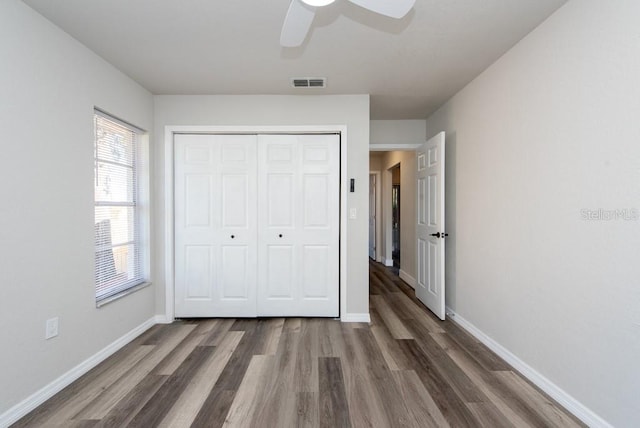 unfurnished bedroom with dark hardwood / wood-style flooring, ceiling fan, and a closet